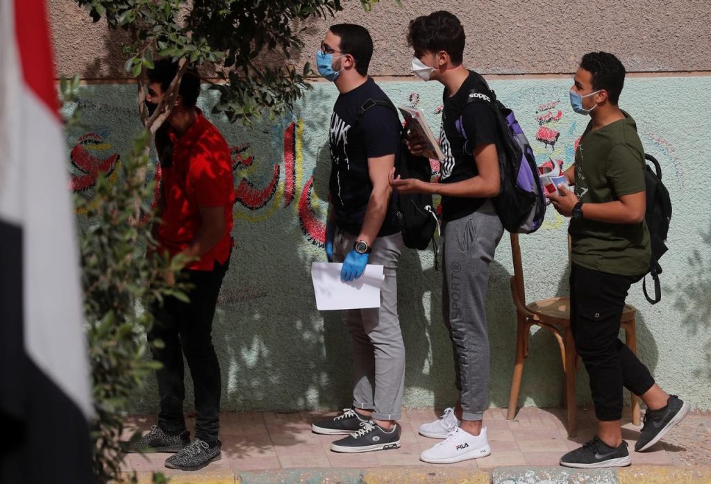 Egyptian high-school students, masked and gloved, head into exams